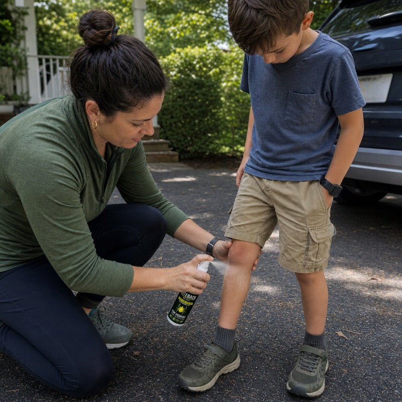 Mom spraying her kid"s bare calf in the driveway